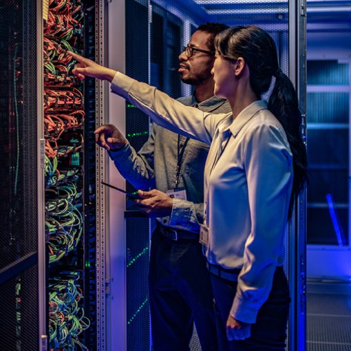 Photo of two IT team members in a server room discussing and troubleshooting the network system