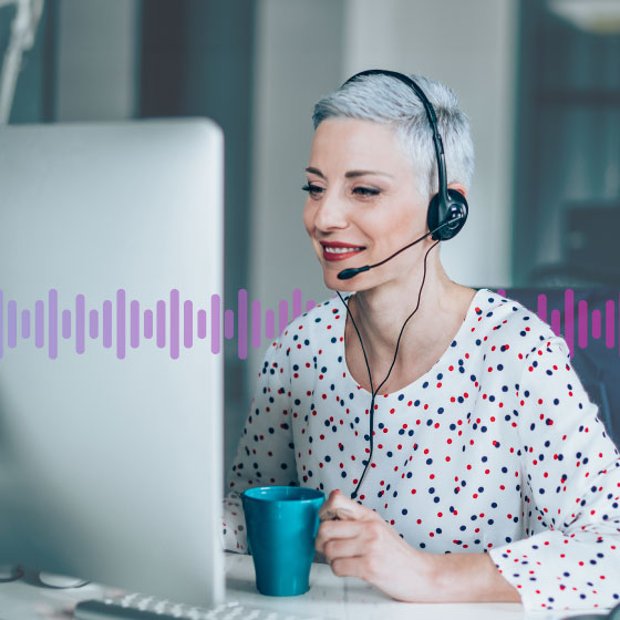 Photo of contact center agent talking to a customer through her headset and looking at her computer screen. Running across the frame are a series of vertical purple lines representing communication.