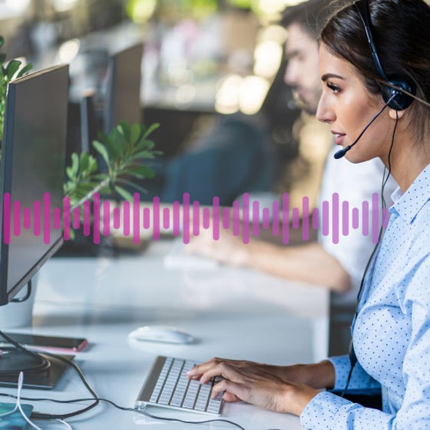 Photo of a call center agent typing data into her computer while taking to a customer on her phone headset. A small row of purple "sound waves" run across the frame representing communication.